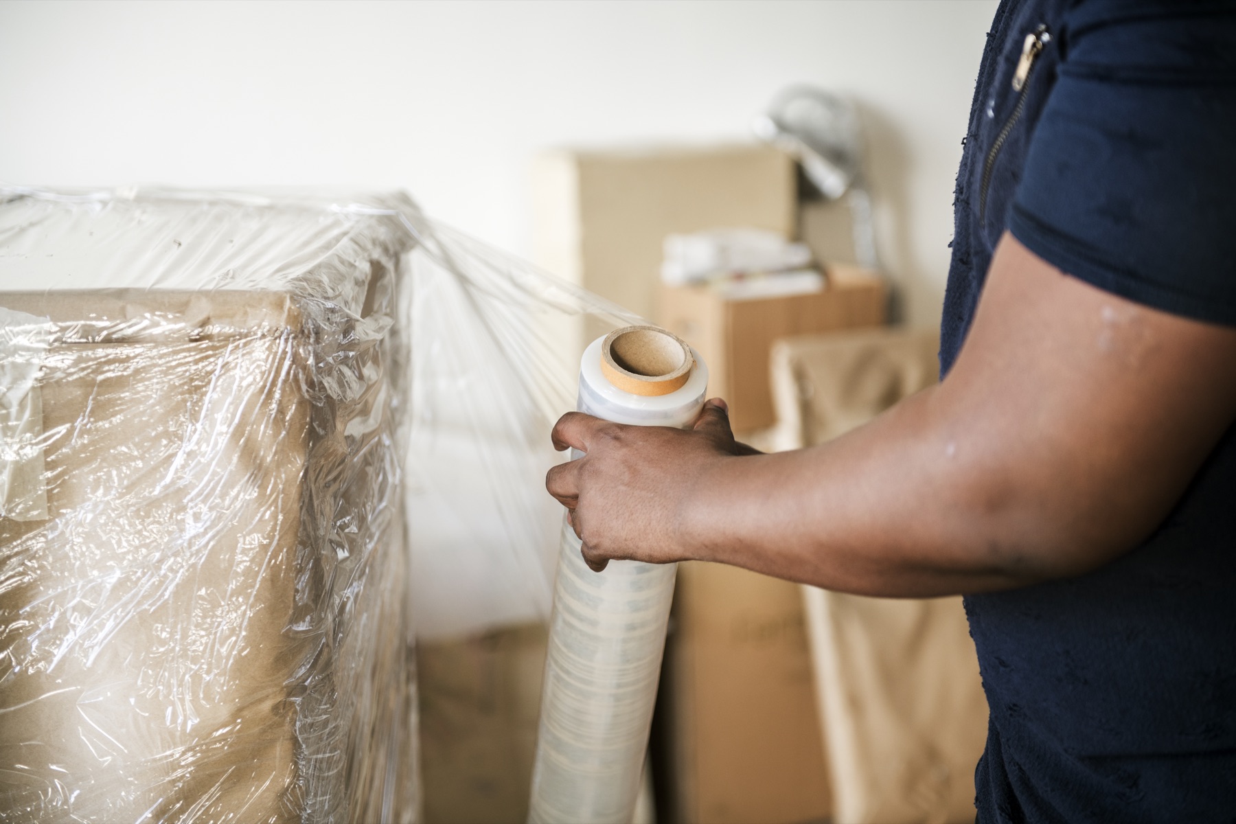 Mover wrapping furniture in protective film before loading