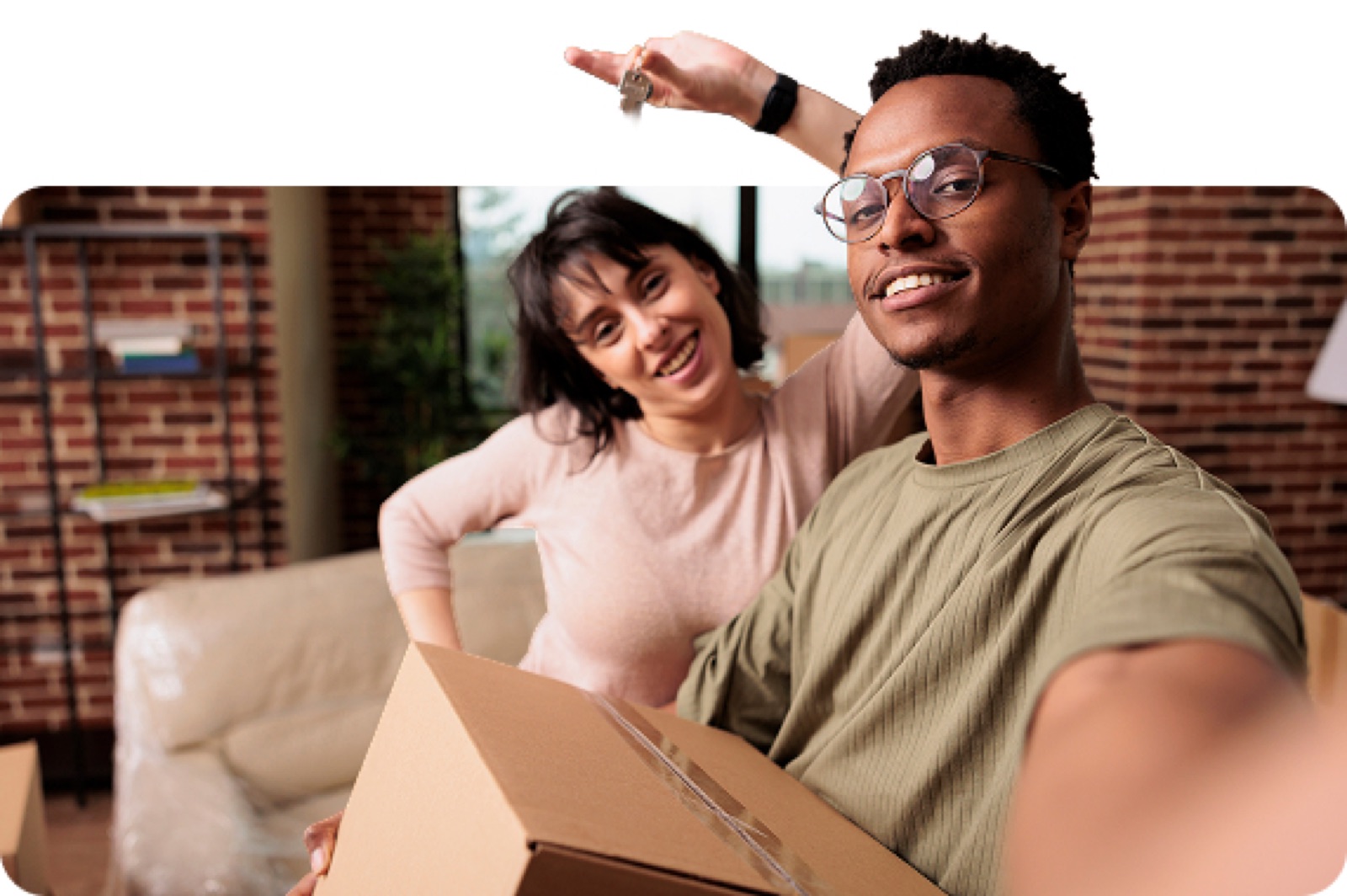 Smiling couple holding the keys and a moving box in their new home